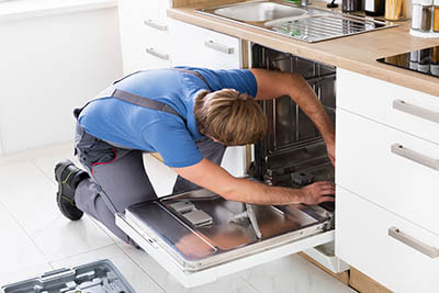 plumber installing dishwasher in renovated kitchen