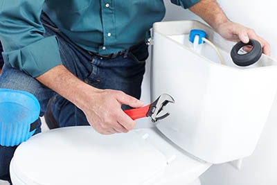 plumber installing new toilet in bathroom